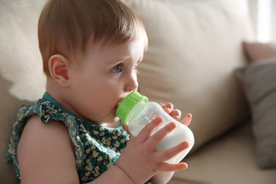 Cute little baby with feeding bottle at home