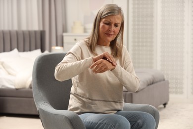 Photo of Mature woman suffering from pain in hand at home. Rheumatism symptom