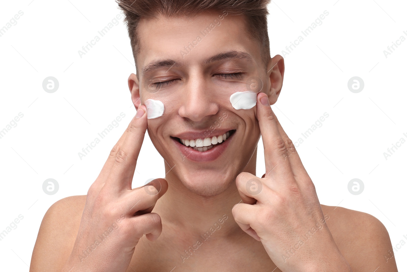 Photo of Handsome man applying moisturizing cream onto his face on white background