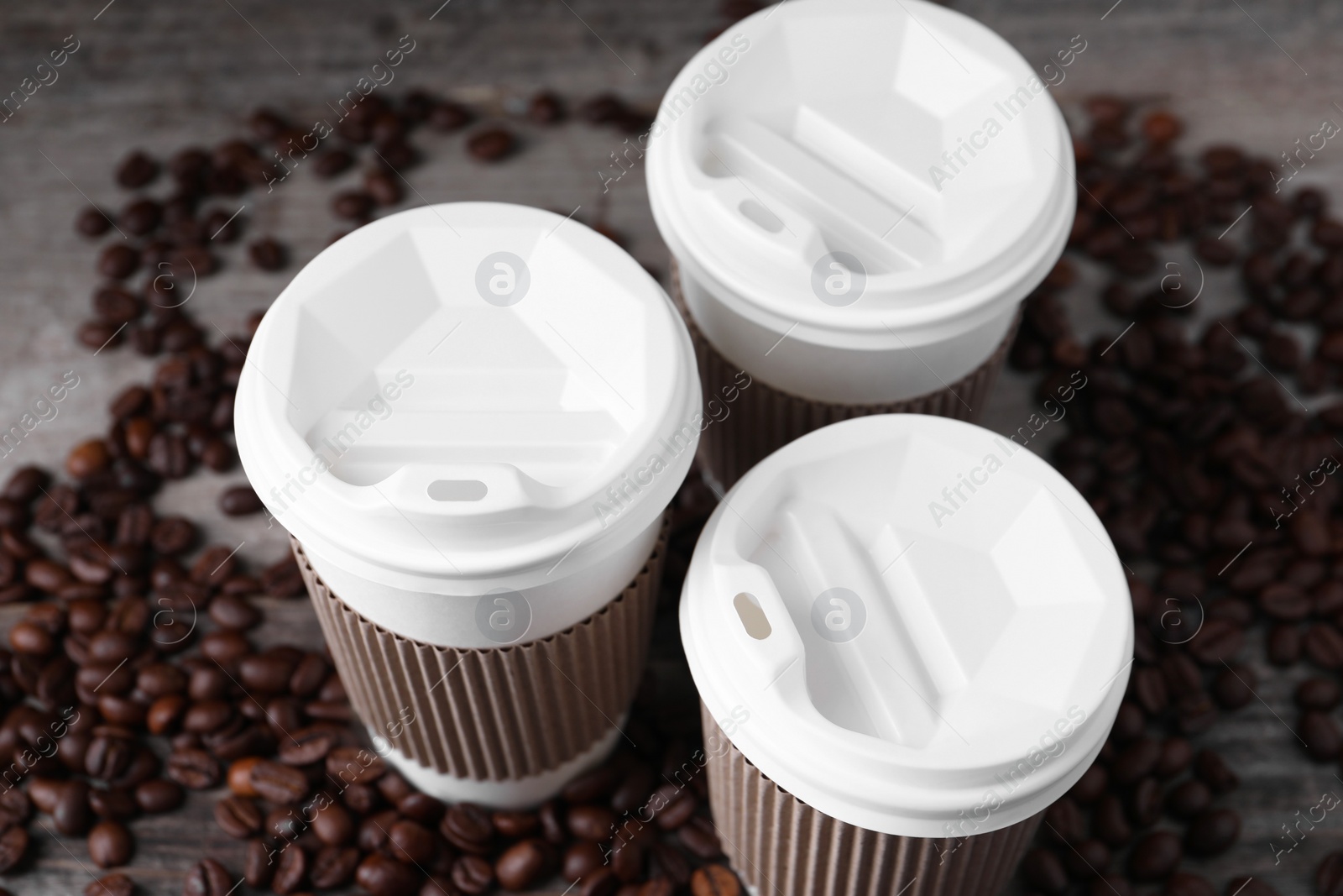 Photo of Coffee to go. Paper cups and roasted beans on table, closeup