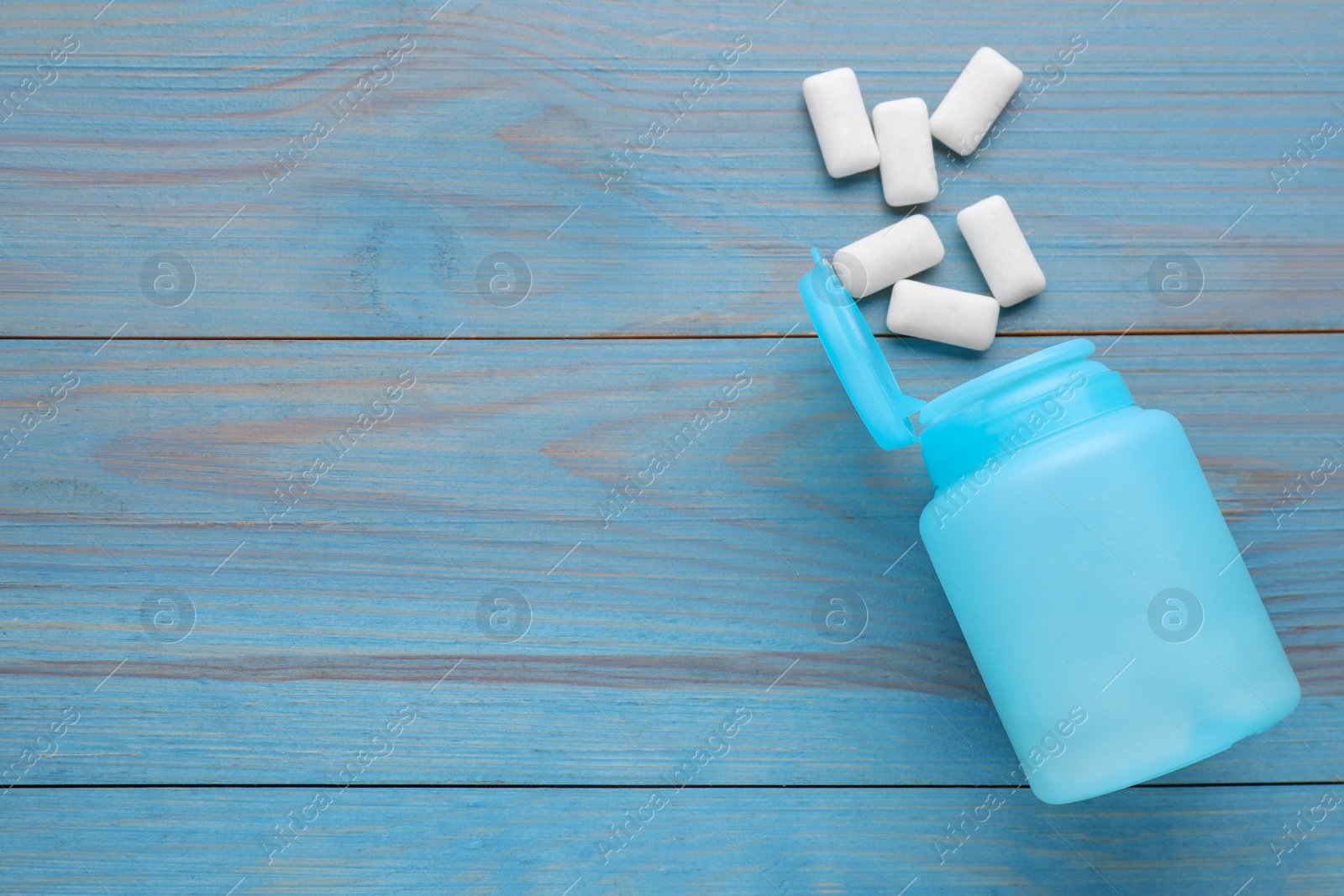 Photo of Jar with chewing gums on light blue wooden table, flat lay. Space for text