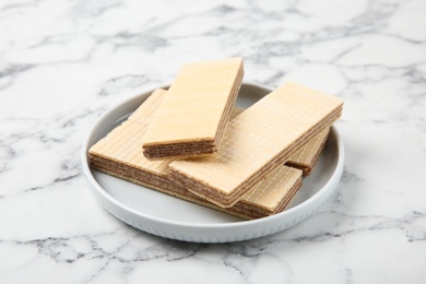 Plate of delicious wafers on marble background