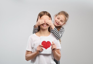 Little daughter congratulating her mom with postcard on white background. Happy Mother's Day