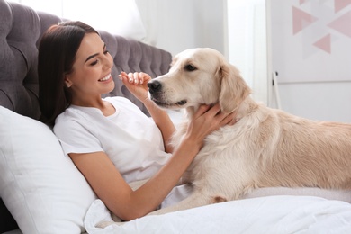 Young woman and her Golden Retriever dog on bed at home