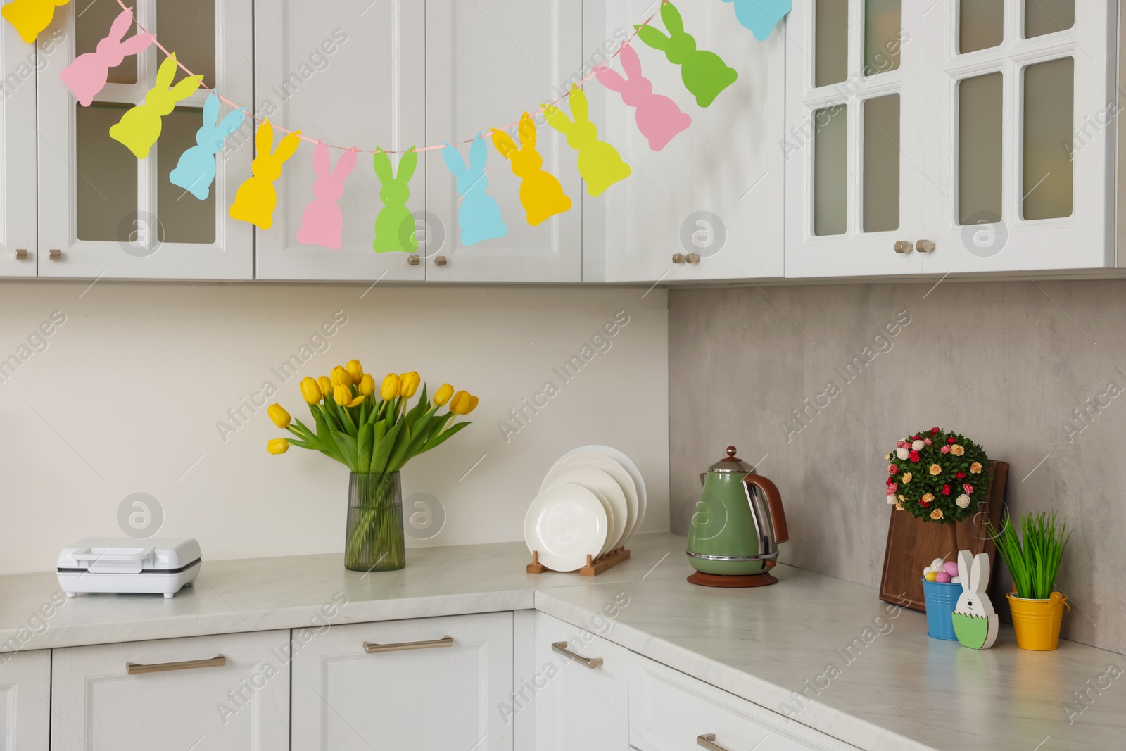Photo of Colorful Easter decor and yellow tulips in kitchen