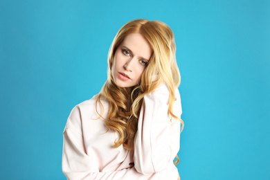 Portrait of beautiful young woman with dyed long hair on blue background