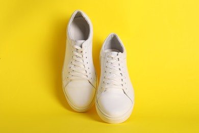 Photo of Pair of stylish white sneakers on yellow background