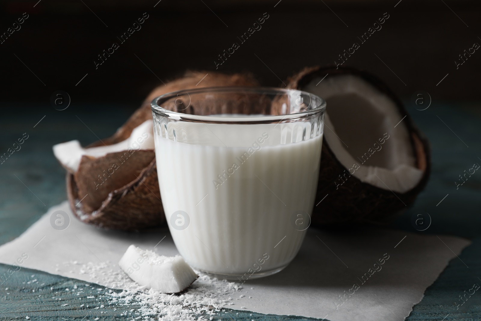 Photo of Glass of delicious coconut milk, flakes and nuts on wooden table