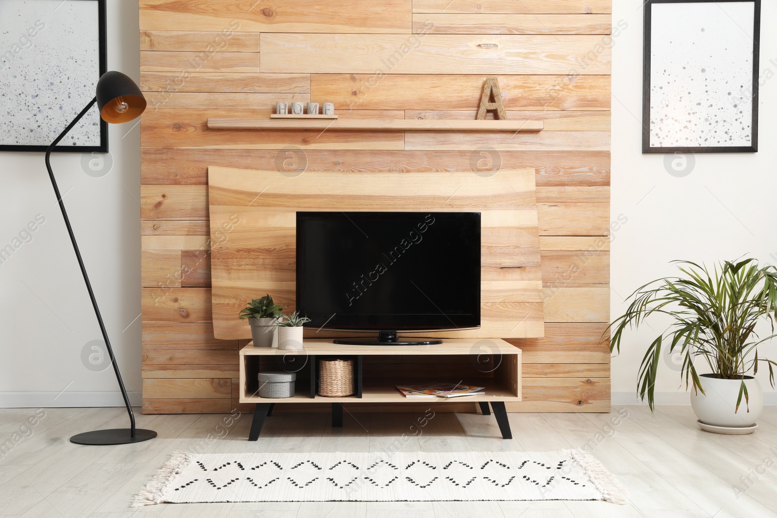 Photo of Modern TV set near decorative wooden wall in living room