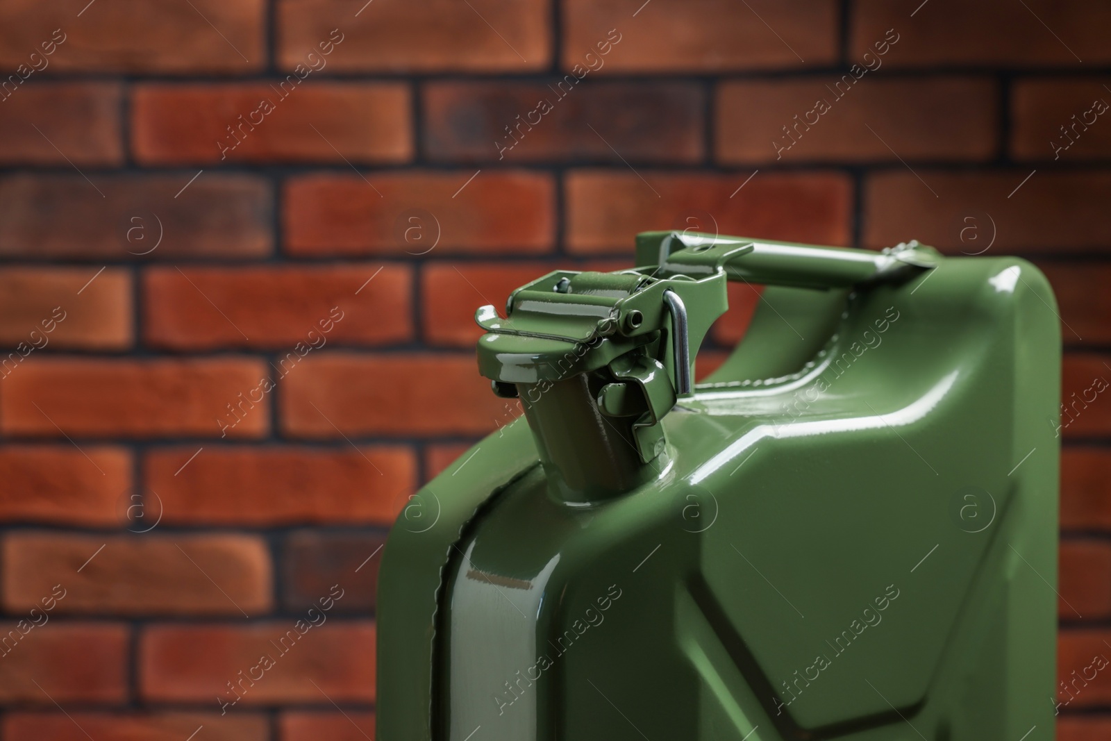 Photo of New khaki metal canister against brick wall, closeup. Space for text