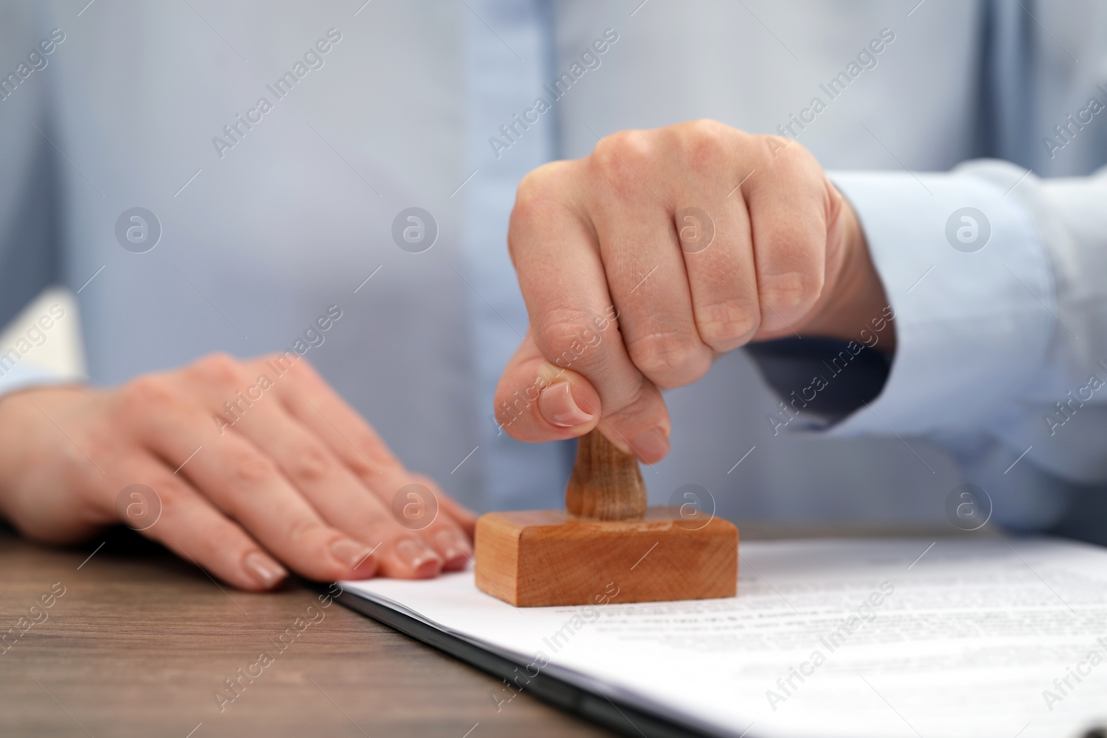 Photo of Woman stamping document at wooden table, closeup