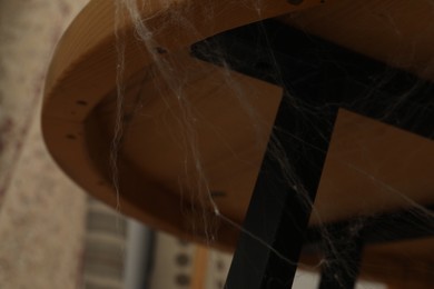 Photo of Old cobweb on wooden table indoors, closeup