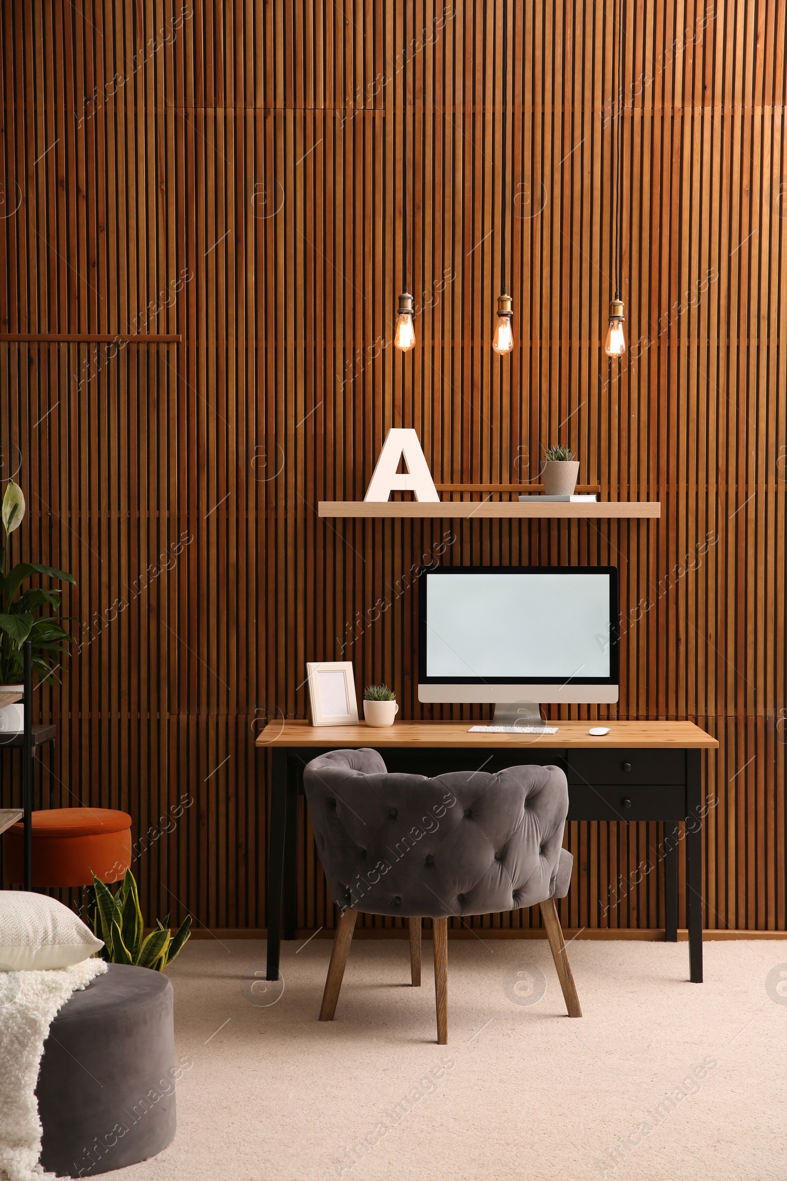 Photo of Comfortable workplace with computer near wooden wall in stylish room interior. Home office design