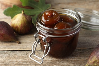 Photo of Jar of tasty sweet jam and fresh figs on wooden table