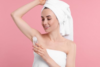 Beautiful woman applying deodorant on pink background