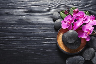 Photo of Composition with orchid flowers and spa stones on dark wooden background, top view. Space for text