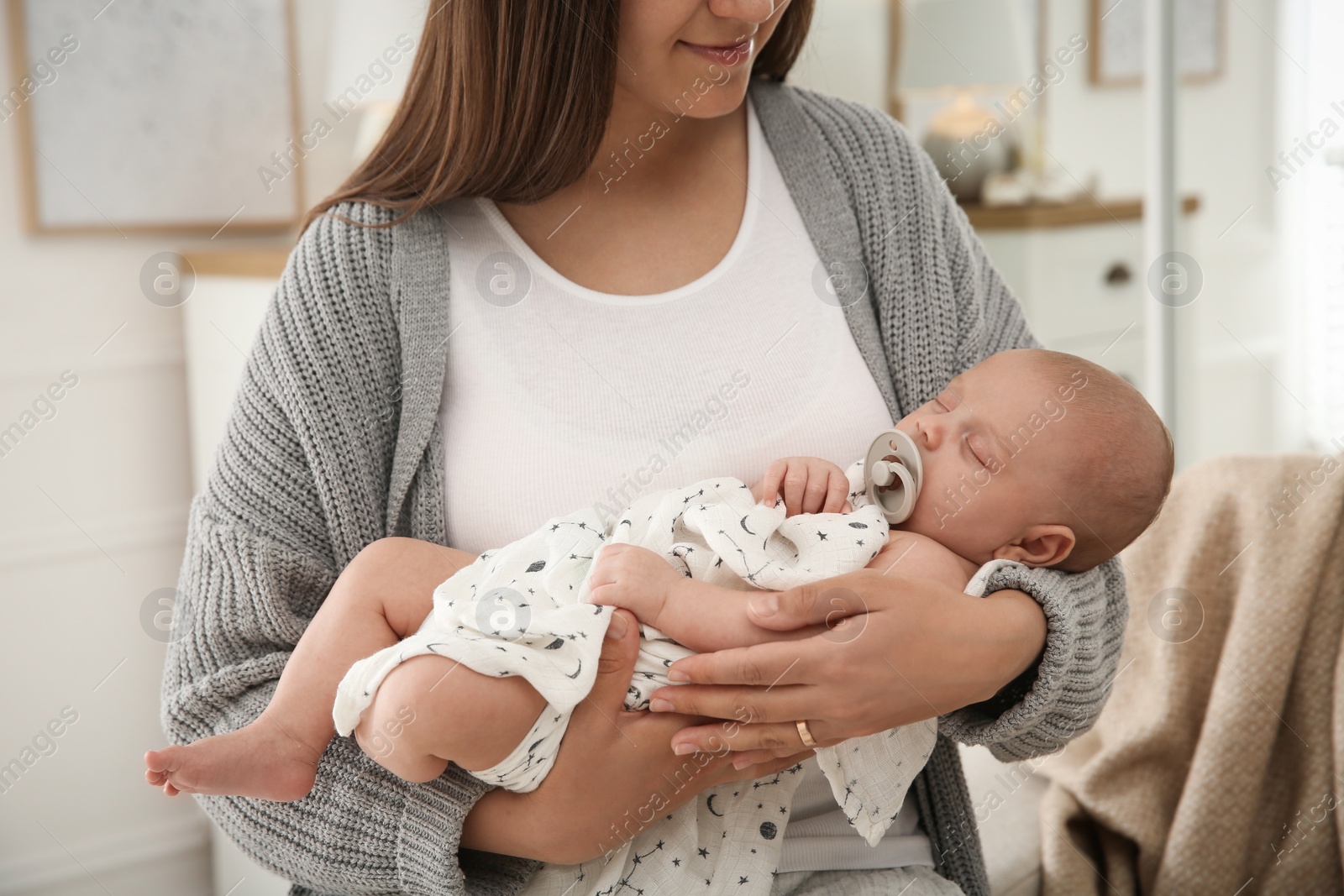 Photo of Mother holding her sleeping baby at home, closeup