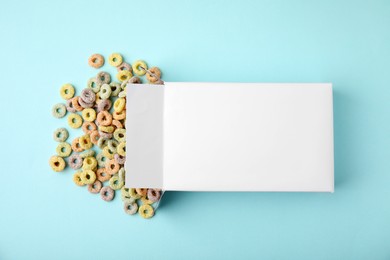 Photo of Paper box with tasty cereal rings on light blue background, flat lay