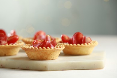 Delicious canapes with jamon on white table, closeup