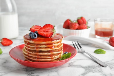 Photo of Plate of delicious pancakes with fresh berries and syrup on white marble table
