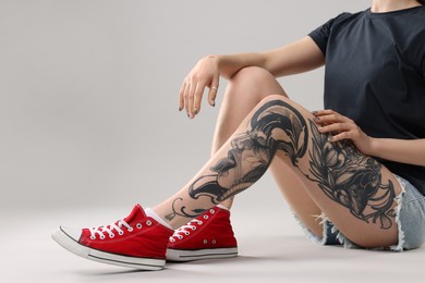 Photo of Woman with cool tattoos on grey background, closeup