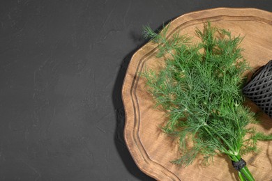 Photo of Bunch of fresh dill and spool of thread on grey table, top view. Space for text
