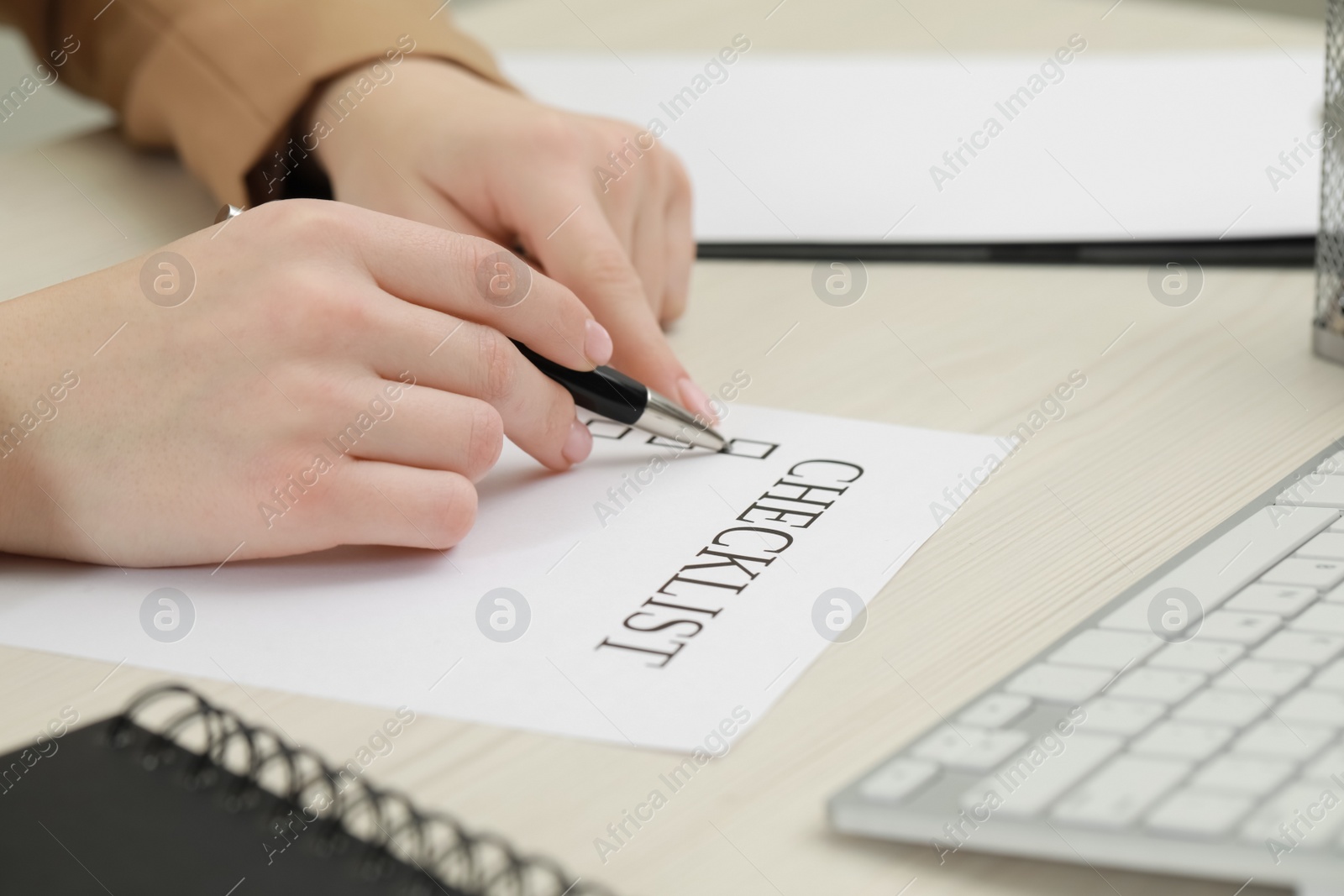 Photo of Woman filling Checklist at white wooden table, closeup