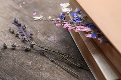 Photo of Beautiful dried flowers and books on wooden table, closeup