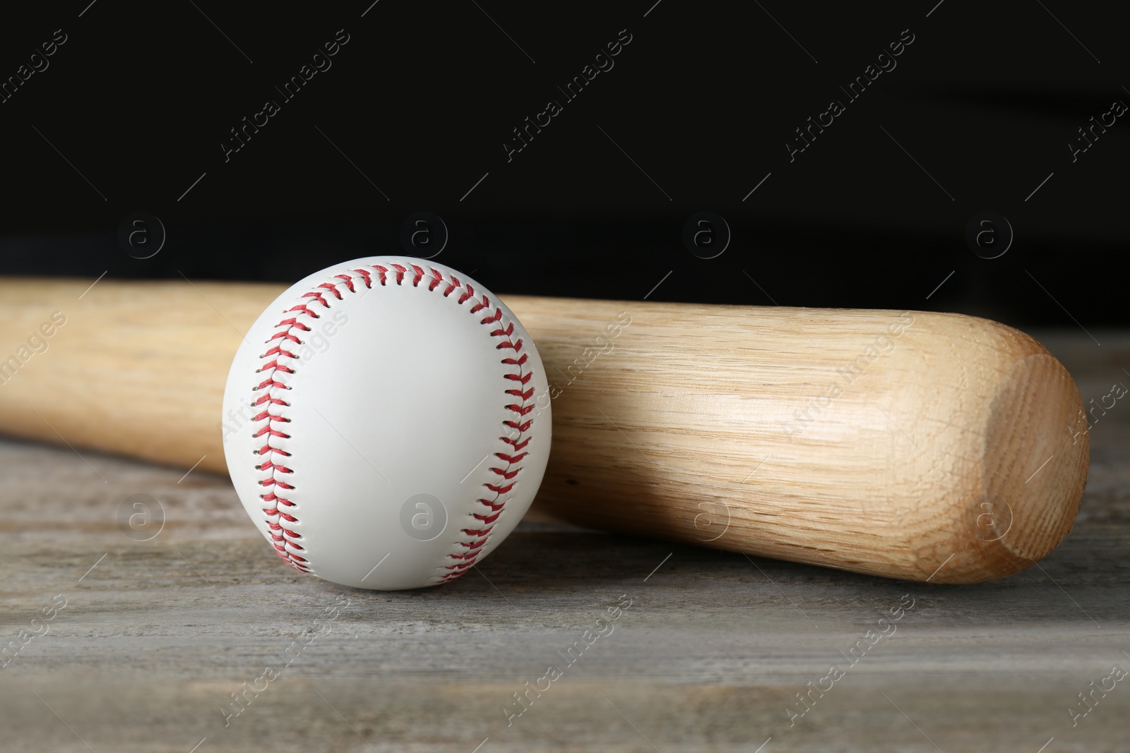 Photo of Baseball bat and ball on wooden table. Sports equipment