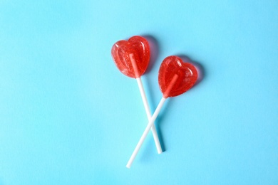 Photo of Heart shaped lollipops on color background, top view. Sweet love
