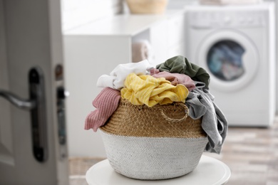 Photo of Wicker basket with dirty laundry on table indoors