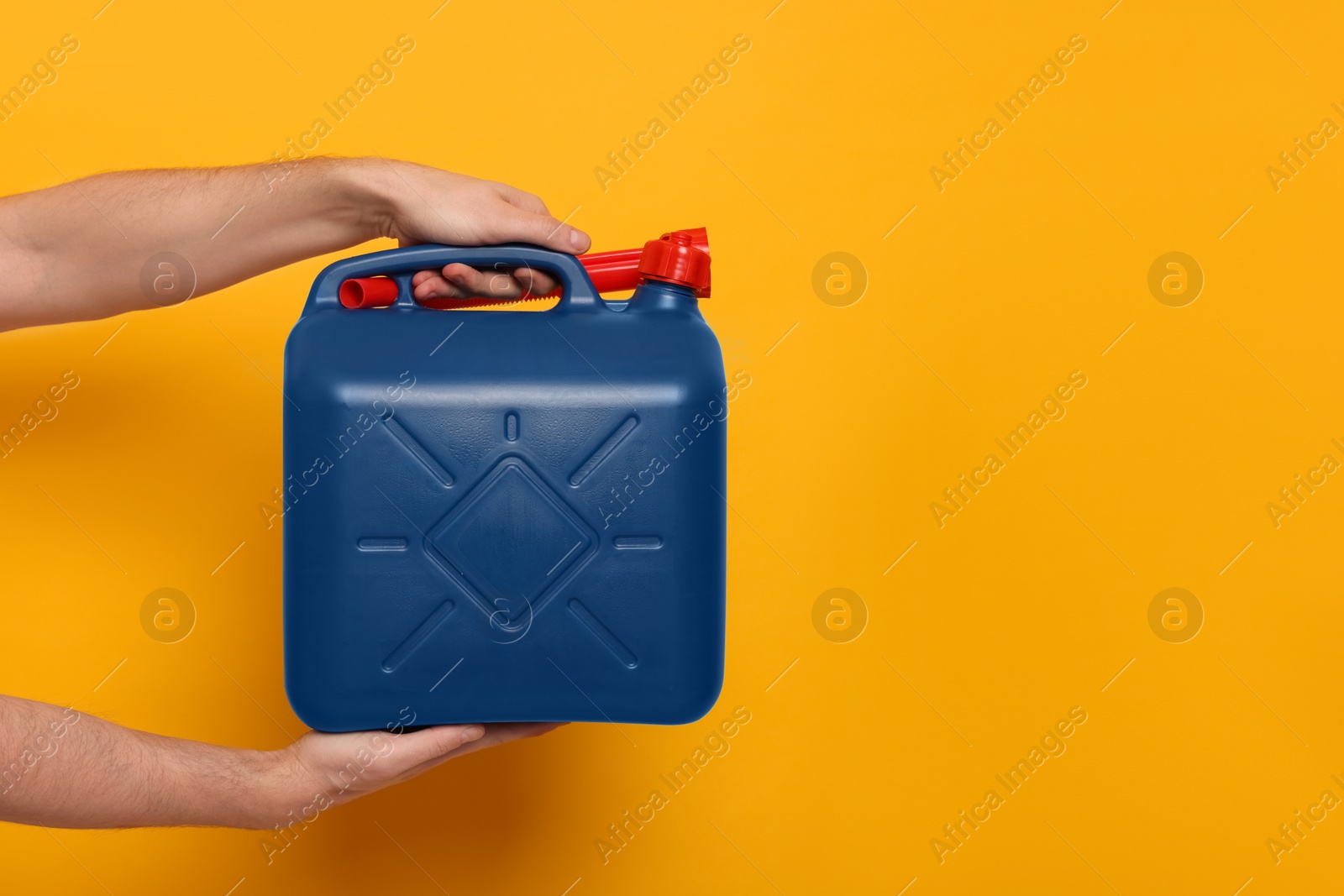 Photo of Man holding blue canister on orange background, closeup. Space for text