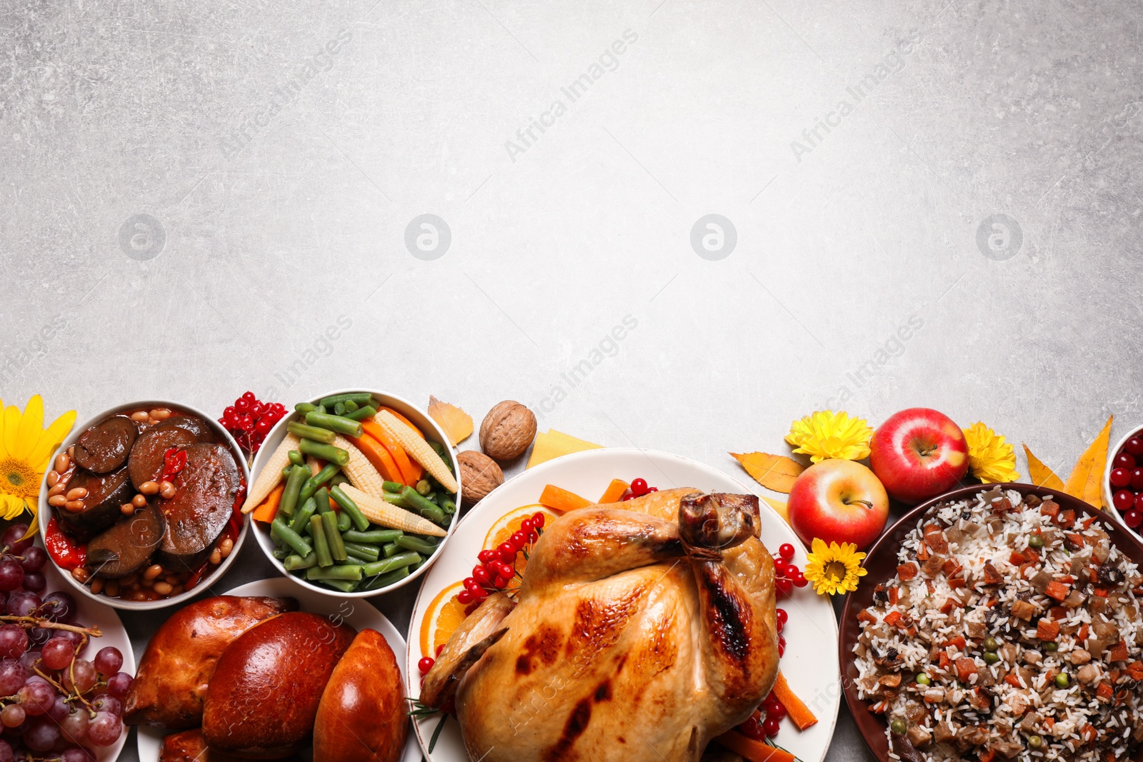 Photo of Traditional Thanksgiving day feast with delicious cooked turkey and other seasonal dishes on light table, flat lay. Space for text