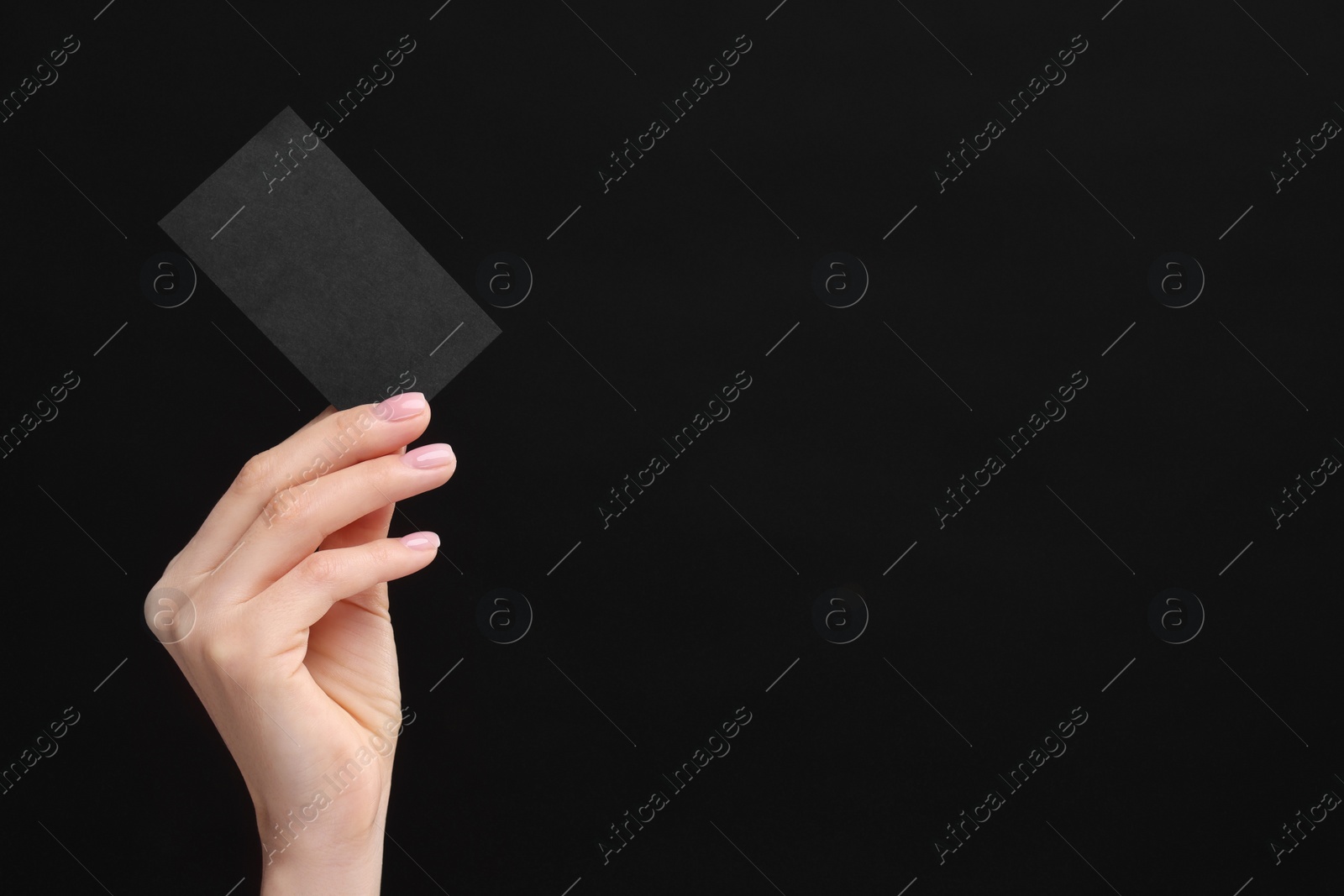 Photo of Woman holding blank business card on black background, closeup. Space for text