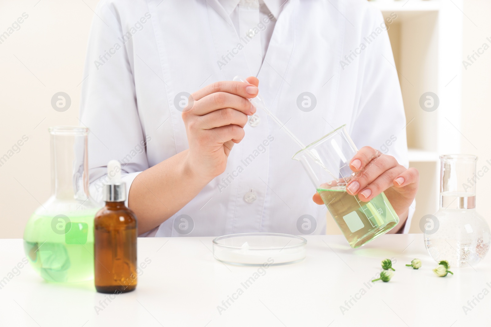 Photo of Female dermatologist creating skin care product at table, closeup