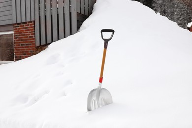 Photo of Metal shovel in large snowbank on winter day