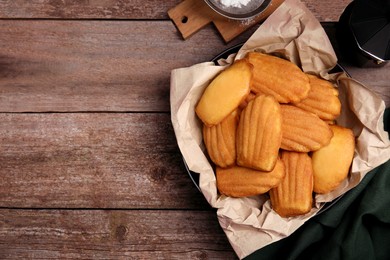 Photo of Delicious madeleine cakes on wooden table, flat lay. Space for text