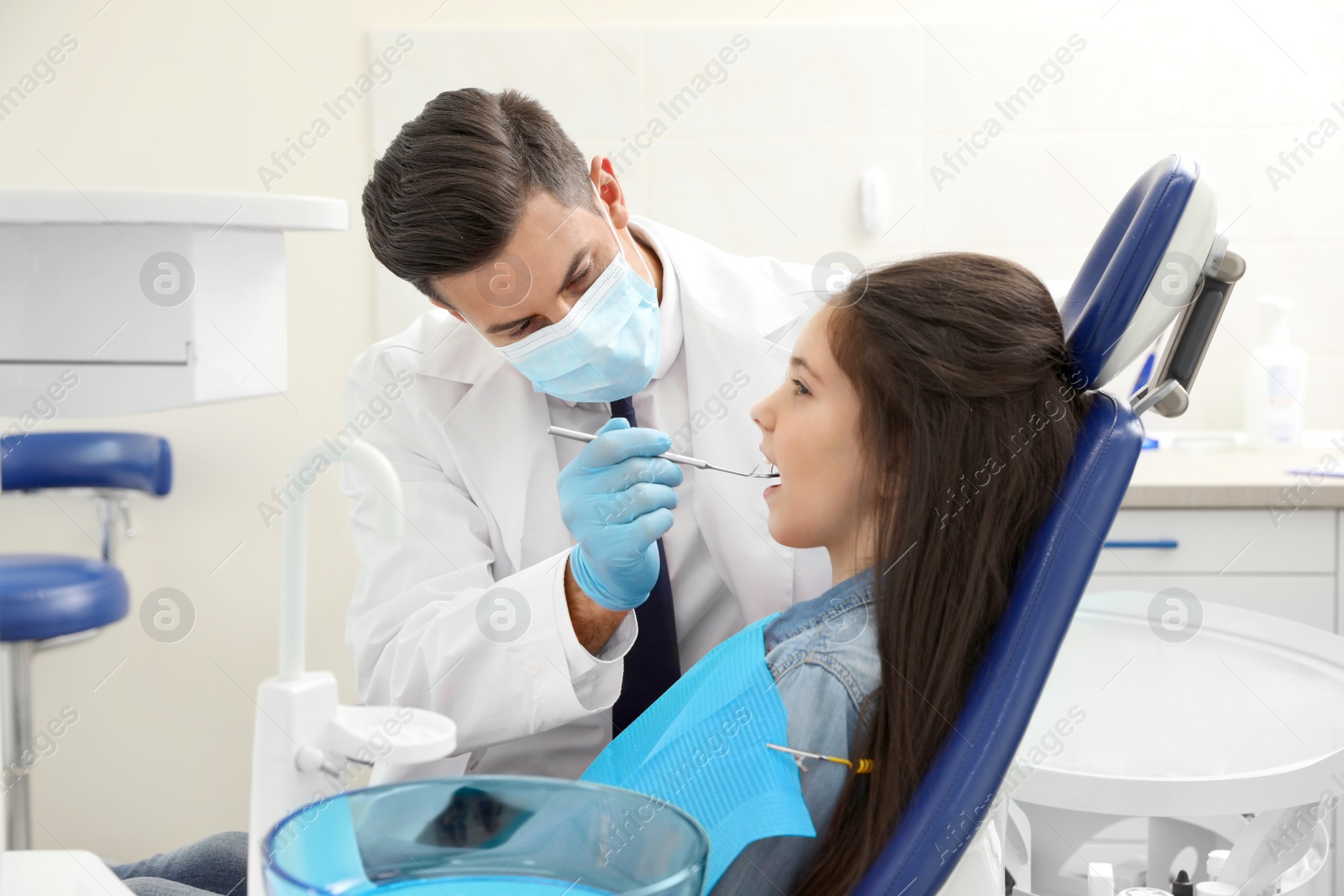 Photo of Professional dentist working with little girl in clinic