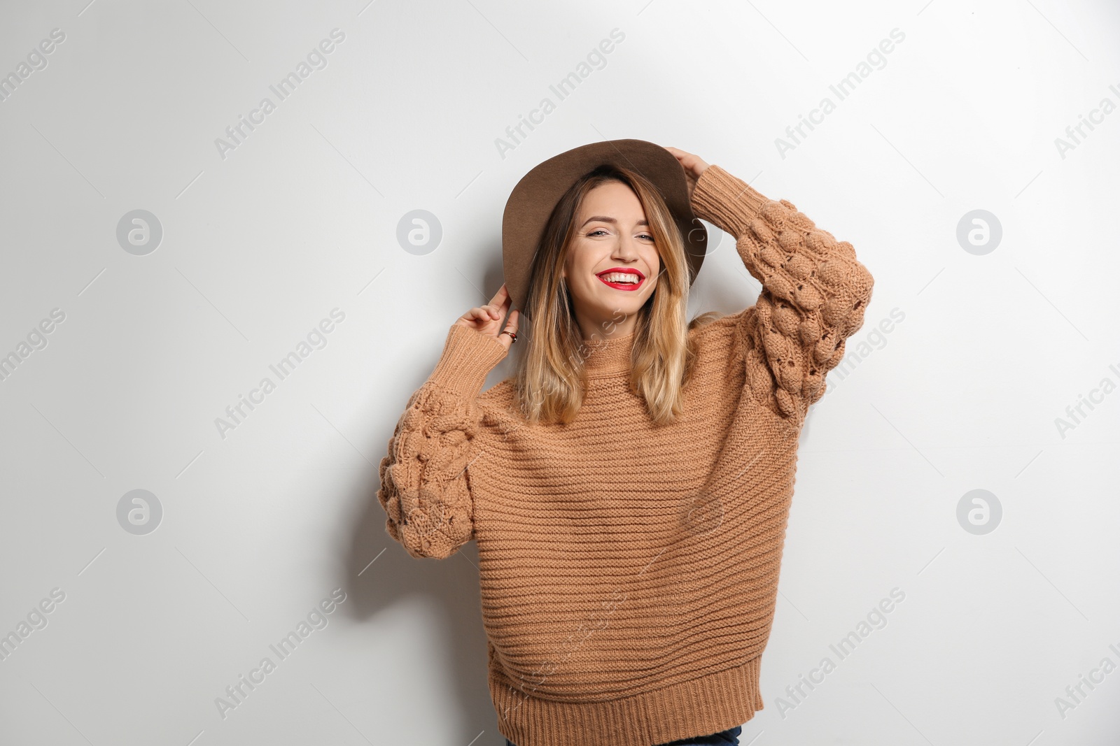 Photo of Beautiful young woman in warm sweater with hat on white background