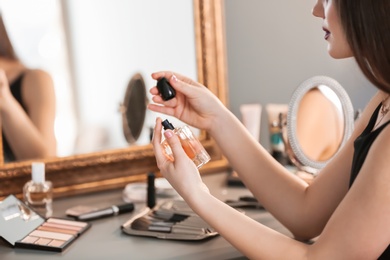 Photo of Young woman applying perfume in makeup room, closeup