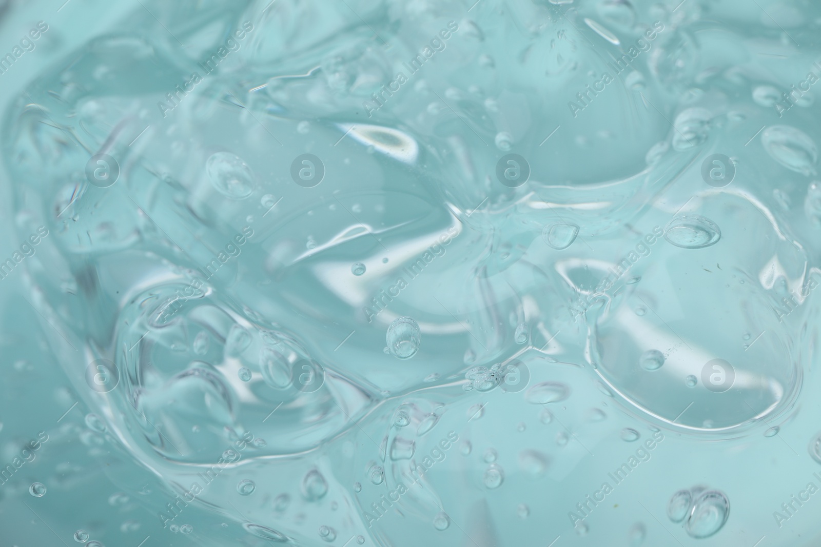 Photo of Pure transparent cosmetic gel on light blue background, closeup