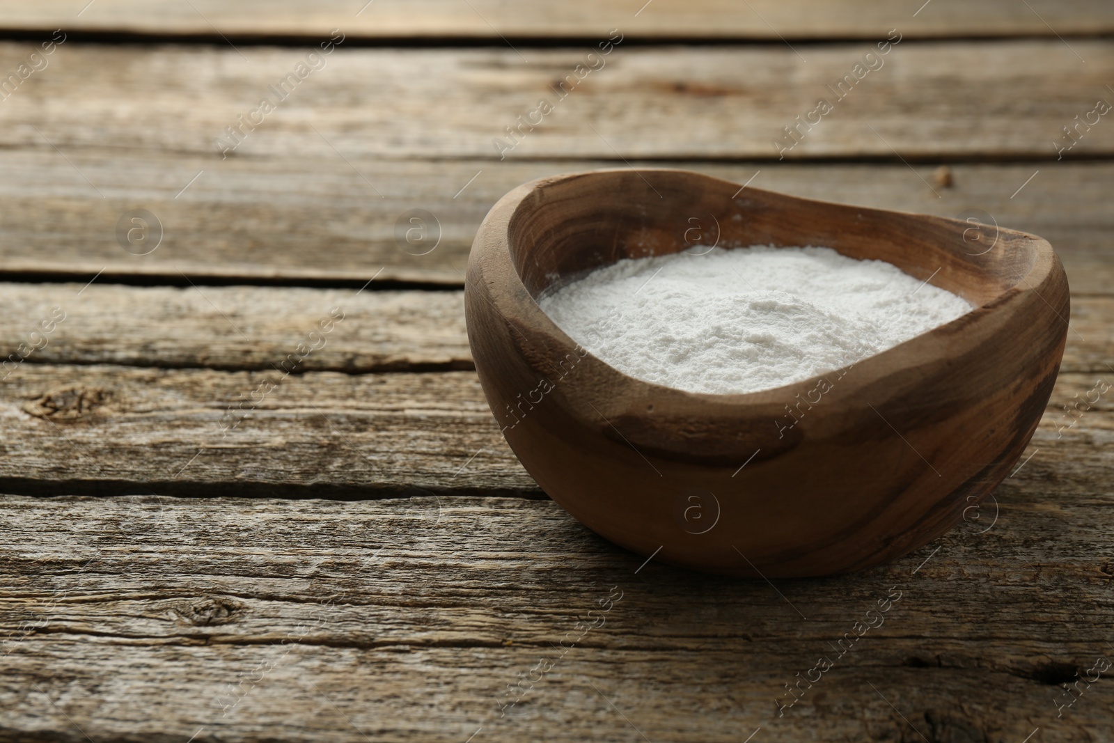 Photo of Baking powder in bowl on wooden table, space for text