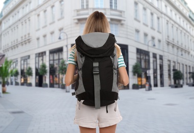 Image of Traveler with backpack in foreign city during summer vacation, back view