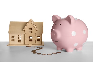 Piggy bank, wooden house model and coins on white background. Saving money concept