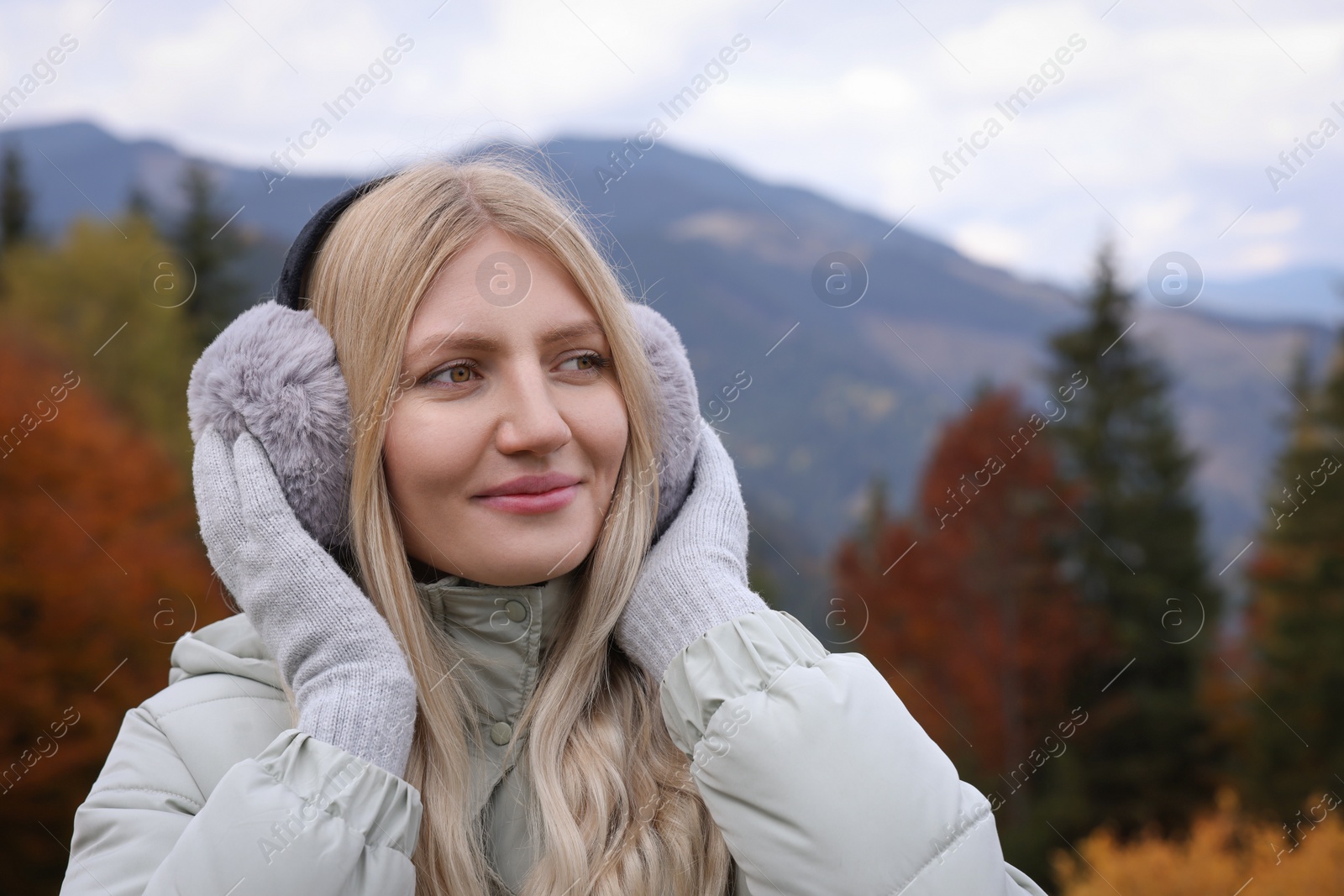 Photo of Young beautiful woman wearing warm earmuffs in mountains
