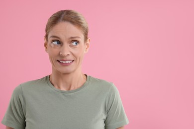 Photo of Embarrassed woman on pink background. Space for text