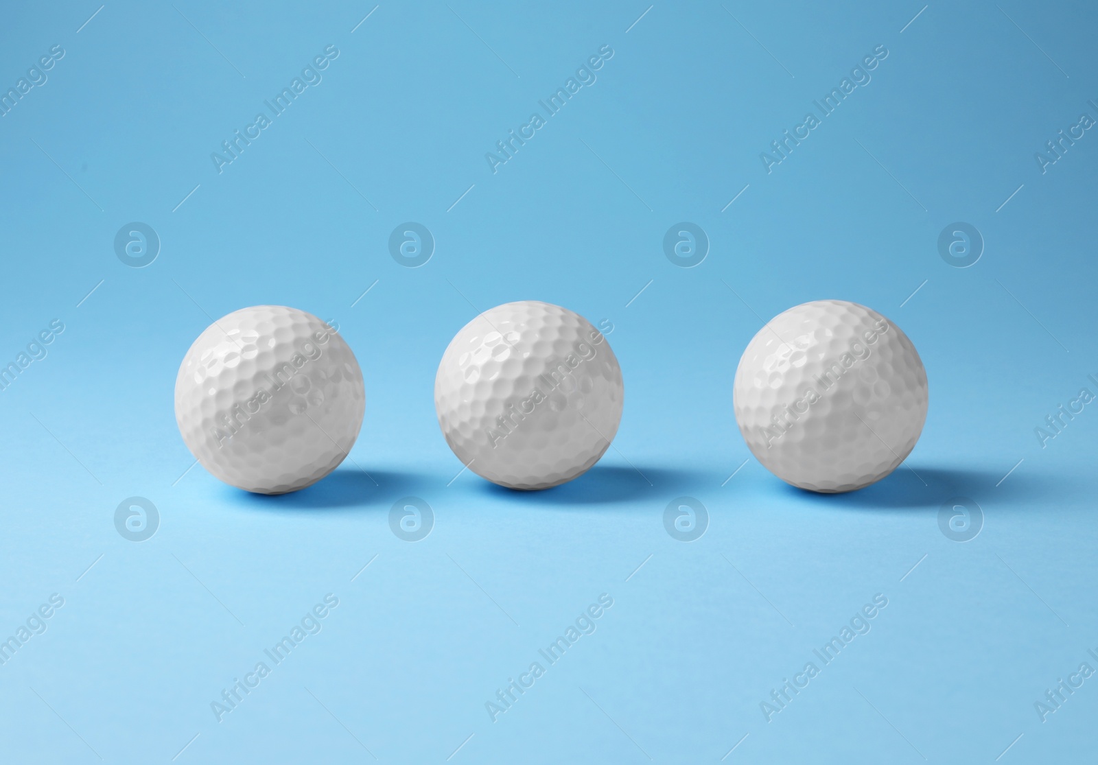 Photo of Three golf balls on light blue background