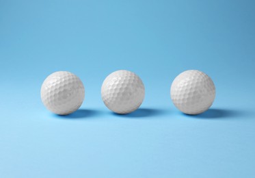 Three golf balls on light blue background