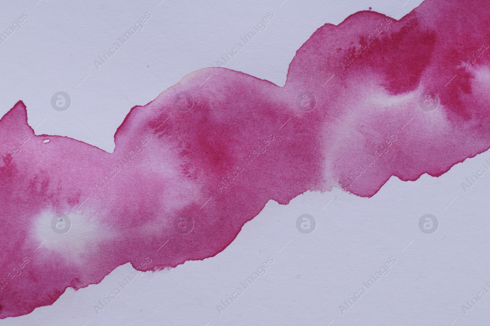 Photo of Blot of pink watercolor paint on white paper, top view