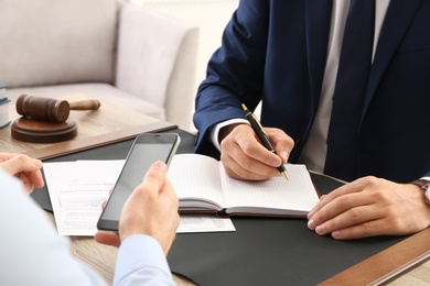 Photo of Lawyer working with client at table in office, focus on hands